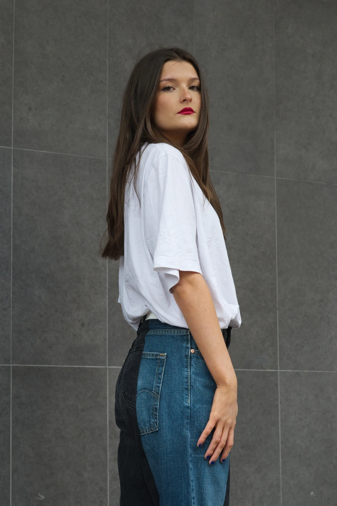The 50s model posing in front of a grey tiled wall.