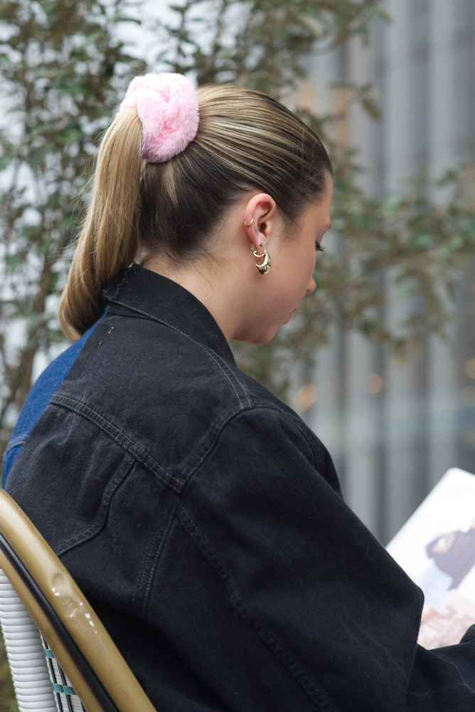 A close up of the 80s model sitting on a chair, reading a magazine.